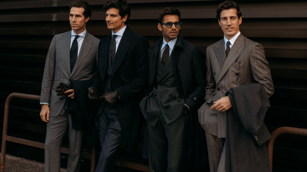Professional examining a variety of men’s suits to show why different suits require different dry cleaning treatment.
